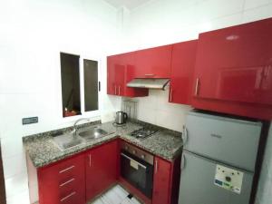 een rode keuken met een wastafel en een koelkast bij City Centre Apartment - New Deco in Tanger