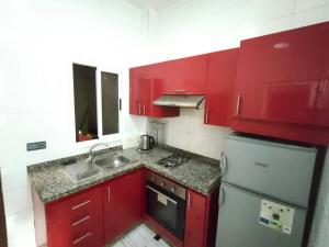 uma cozinha vermelha com um lavatório e um frigorífico em City Centre Apartment - New Deco em Tânger