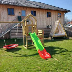 un parque infantil con 2 toboganes y un columpio en Ferienwohnung Familie Roth, en Rückholz