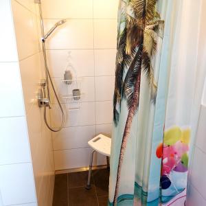 a bathroom with a shower with a palm tree shower curtain at Ferienwohnung Familie Roth in Rückholz