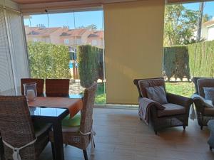 ein Esszimmer mit einem Tisch und Stühlen sowie einem großen Fenster in der Unterkunft Adosado playa Islantilla campo de golf in Huelva