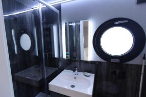 a bathroom with a sink and a round mirror at Hausboot Fjord Aquila mit Dachterrasse in Wendtorf in Wendtorf