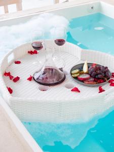 due bicchieri di vino e frutta su un vassoio in piscina di BlackRock suites a Karterados