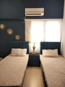 1 dormitorio con 2 camas y mesita de noche con lámpara en The Realtors Inn 2 BDR Apartment en Islamabad