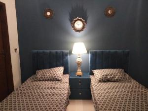 1 dormitorio con 2 camas y mesita de noche con lámpara en The Realtors Inn 2 BDR Apartment en Islamabad