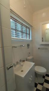 een witte badkamer met een toilet en een wastafel bij Touraco in Hogsback