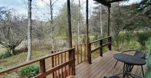 una terraza de madera con mesa y taburete. en Touraco en Hogsback