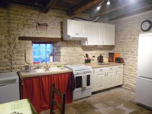 a kitchen with white cabinets and a stove top oven at Gîte La Roussette 3 étoiles in Fresnes