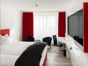 Habitación de hotel con cama y escritorio con sillas en DORMERO Hotel Darmstadt, en Darmstadt