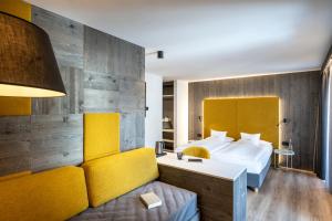 um quarto de hotel com uma cama e um sofá em Hotel Ladinia Dolomites View em Pozza di Fassa