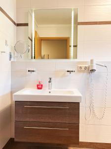ein Bad mit einem Waschbecken und einem Spiegel in der Unterkunft FeWo-Zimmer-Auszeit in Drahnsdorf