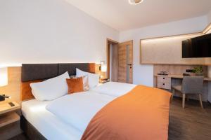 a bedroom with a large white bed and a desk at Hotel Trattnig in Döbriach