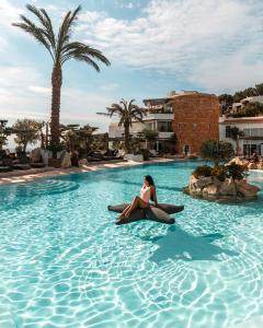 a woman is sitting in a swimming pool at Hacienda Na Xamena, Ibiza in Na Xamena