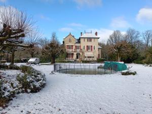 a large house with a fence in the snow at Le Pavillon de St Agnan in Hautefort
