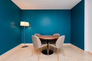 a table and chairs in a room with a blue wall at Los Robles Stylish & Modern 1 Bedroom Apartment in Madrid Conde Orgaz in Madrid