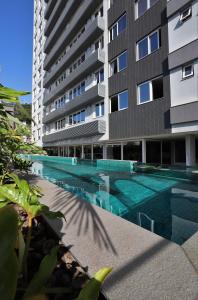 a swimming pool in front of a building at Patio Milano Apartamentos completos em condominio incrivel com food hall in Florianópolis