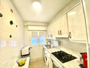 cocina con armarios blancos y fogones en Apartamento Cebra, en Zaragoza