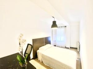 1 dormitorio con cama blanca y mesa negra en Apartamento Cebra, en Zaragoza