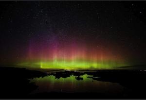 an aurora in the sky with a reflection in the water at Borve House, Kilchoan in Kilchoan