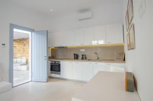 a kitchen with white cabinets and a sink at Theros apartments 1 in Mylopotas
