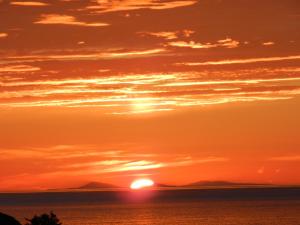 a sunset over the ocean with the sun in the sky at Borve House, Kilchoan in Kilchoan