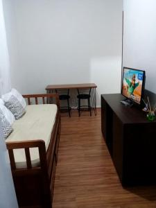 1 dormitorio con 1 cama y 1 mesa con TV en Apartamento aconchegante no centro de Teresópolis ( várzea), en Teresópolis