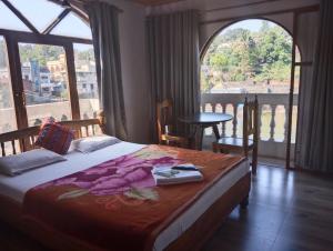 ein Schlafzimmer mit einem Bett und einem großen Fenster in der Unterkunft Magadh ,In Fort Panhala Hotel in Panhāla