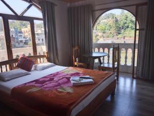 a bedroom with a bed and a large window at Magadh ,In Fort Panhala Hotel in Panhāla