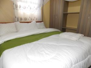 un grande letto bianco con lenzuola bianche e coperta verde di Cloud9 Suites a Kitale