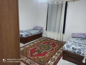 a bedroom with two beds and a rug on the floor at عين النعجة جسر قسنطينة الجزائر Ain Naadja 