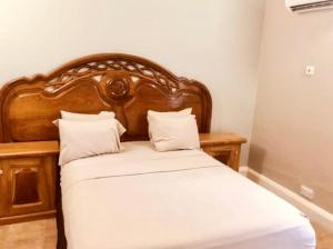 a bed with a wooden headboard and two pillows at Summer Grove Villa in Kololi