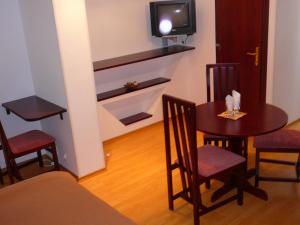um pequeno quarto com uma mesa e cadeiras e uma televisão em Casa iRMA - Rooms for rent em Bacau