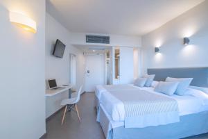 a hotel room with two beds and a desk with a computer at Hotel El Puerto by Pierre Vacances in Fuengirola