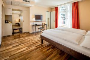 1 dormitorio con 1 cama grande y escritorio en Hotel Schweizerhof Basel, en Basilea