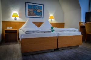 2 Einzelbetten in einem Zimmer mit 2 Lampen in der Unterkunft Hotel Aulmann in Trier