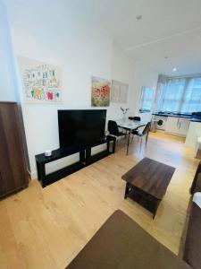 a living room with a flat screen tv and a table at Amazing 2 bedroom apartment in London