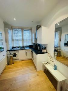 a kitchen with white cabinets and a bench in it at Amazing 2 bedroom apartment in London