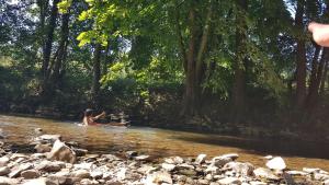 Eine Frau sitzt im Wasser eines Flusses in der Unterkunft O'Noire, Viroinval Treignes in Treignes