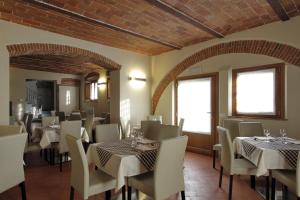 un restaurant avec des tables blanches, des chaises et des fenêtres dans l'établissement Agriturismo San Martino, à Quarrata