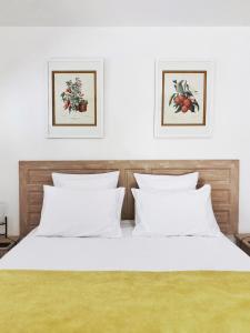 a bedroom with a white bed with two pictures on the wall at ESCAPADE BELLEPIERRE (L') in Saint-Denis