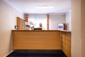 a man standing behind a reception desk in a room at acora Bonn Living the City - Apartments in Bonn