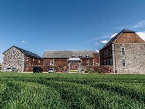 un gran edificio de ladrillo con un campo de hierba delante de él en Beautiful Cottage with Pool, en Ohey
