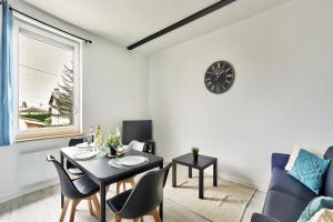 - un salon avec une table, des chaises et une horloge dans l'établissement Appartement Le Cocon Bressan, à Bourg-en-Bresse