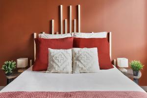 Una cama con almohadas rojas y blancas. en Appartement Le Cocon Bressan en Bourg-en-Bresse