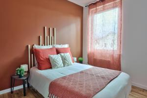 1 dormitorio con 1 cama con paredes de color naranja y ventana en Appartement Le Cocon Bressan en Bourg-en-Bresse