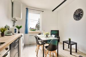 une cuisine avec une table, des chaises et une horloge murale dans l'établissement Appartement Le Cocon Bressan, à Bourg-en-Bresse