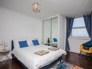 a bedroom with a bed with blue pillows and a window at Large House, sleeps 10 with incredible sea views in Ilfracombe