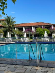 a swimming pool in front of a hotel with tables and chairs at Le Corsaire in Búzios