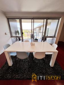 un tavolo bianco con sedie in una stanza con finestra di Spacious 1bd Penthouse - Close to ANU a Canberra