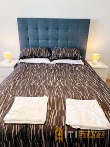 un letto con testiera blu e 2 cuscini di Spacious 1bd Penthouse - Close to ANU a Canberra